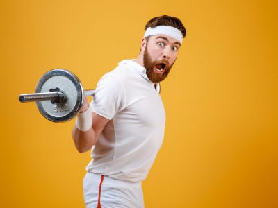 Portrait of an excited bearded fitness man workout with barbell isolated on a white background